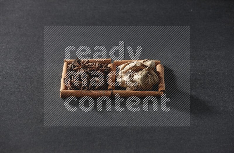 2 squares of cinnamon sticks full of star anise and dried ginger on black flooring