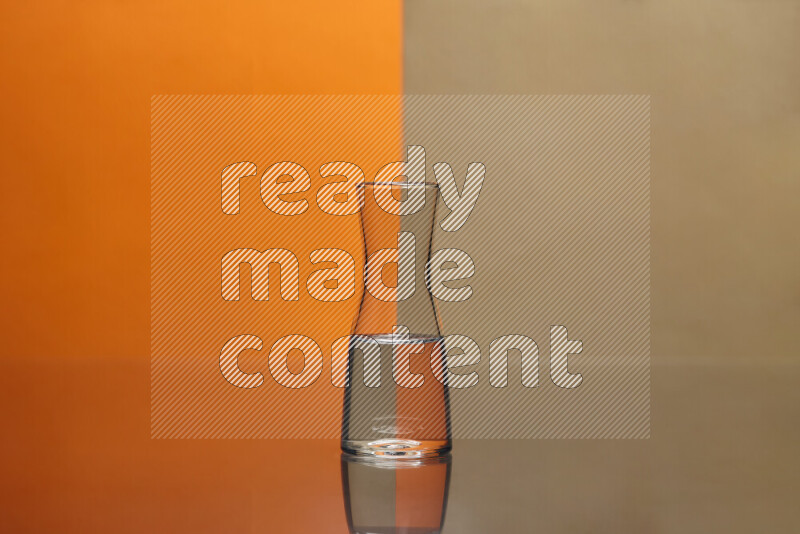The image features a clear glassware filled with water, set against orange and beige background