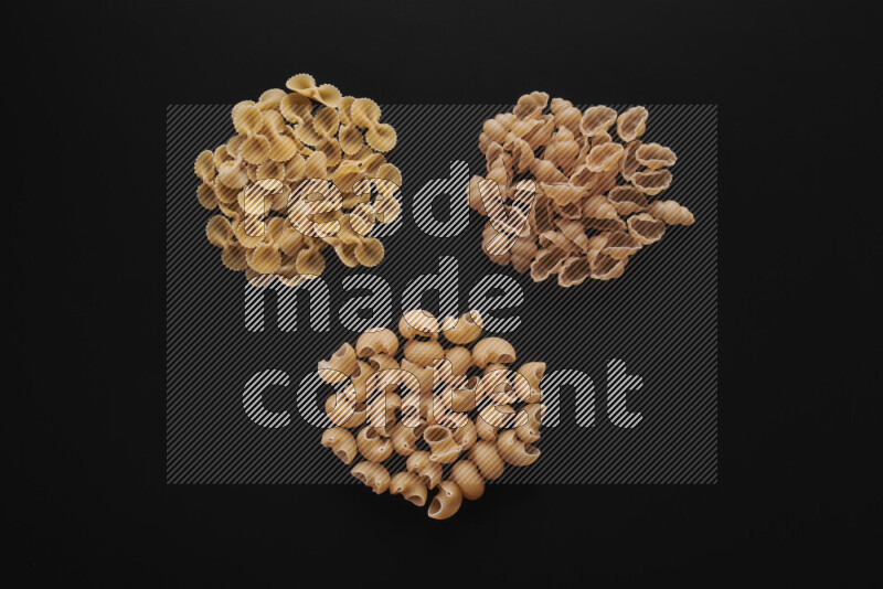 Different pasta types in bunches on black background