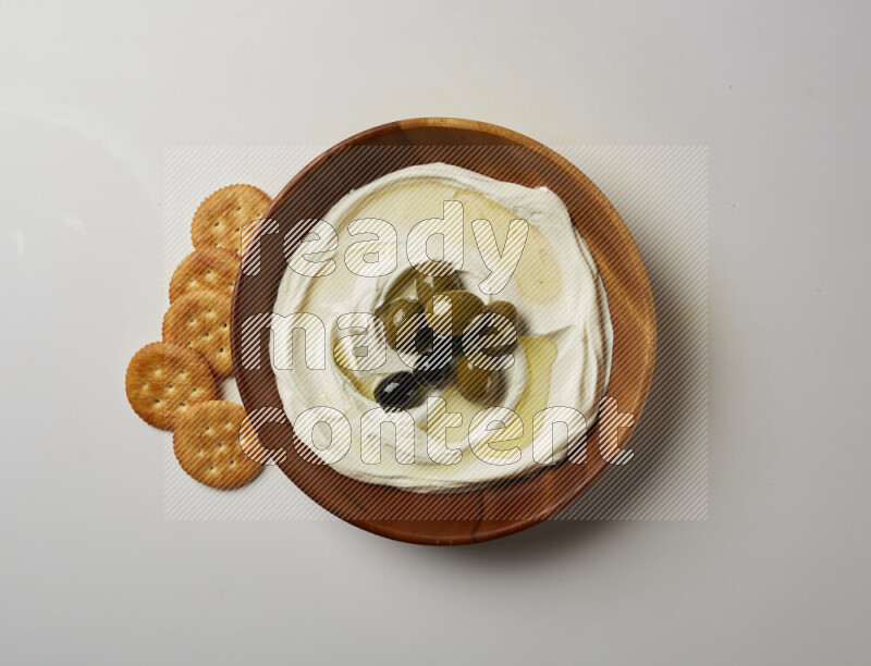 Lebnah garnished with whole olives in a wooden plate on a white background