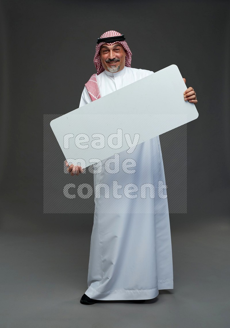 Saudi man with shomag Standing holding social media sing on gray background