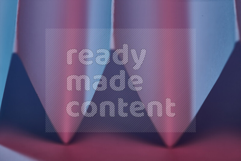 صورة مجردة مقربة تظهر طيات ورقية هندسية حادة بتدرجات اللون الأزرق والوردي