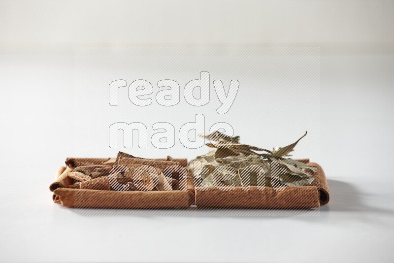2 squares of cinnamon sticks full of cinnamon and bay laurel leaves on white flooring