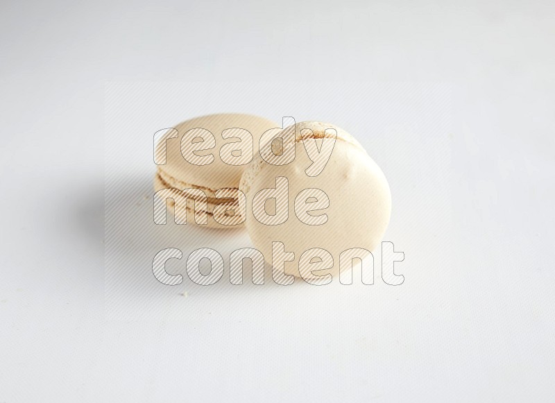 45º Shot of two White Caramel fleur de sel macarons on white background