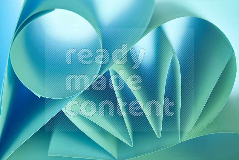 An artistic display of paper folds creating a harmonious blend of geometric shapes, highlighted by soft lighting in green and blue tones
