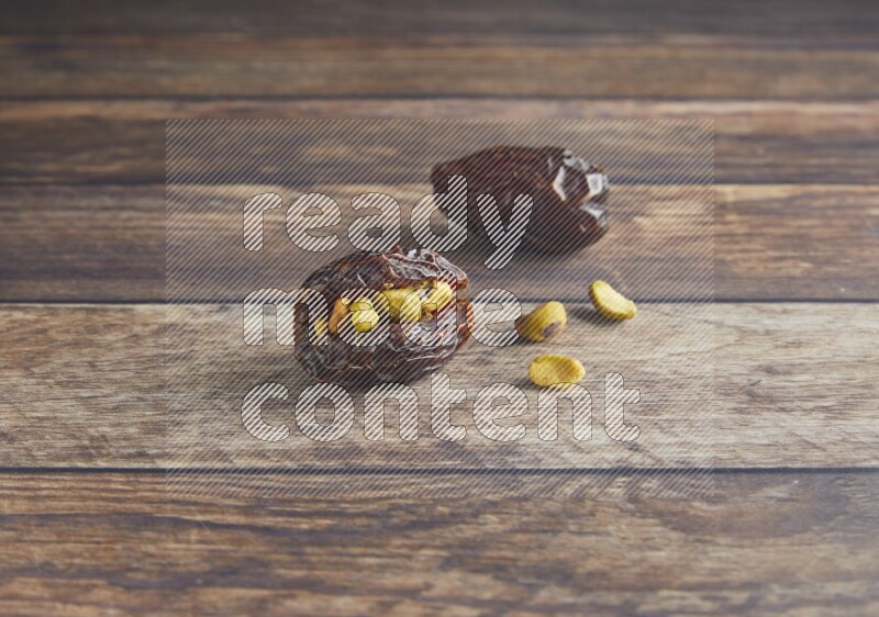two pistachio stuffed madjoul date on a wooden background