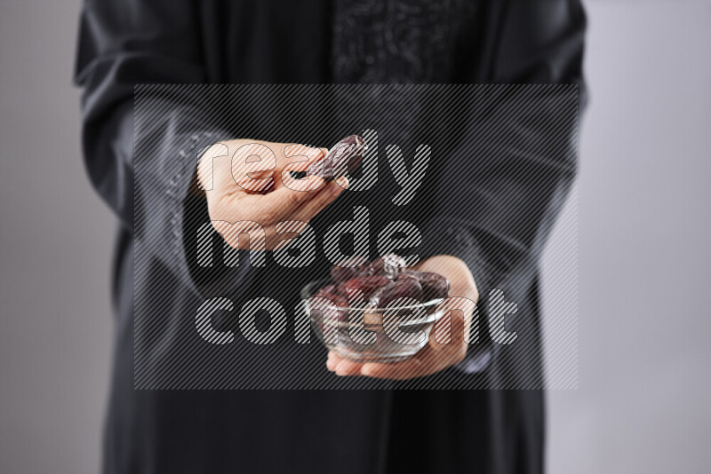 Woman in abaya holding dates in different positions
