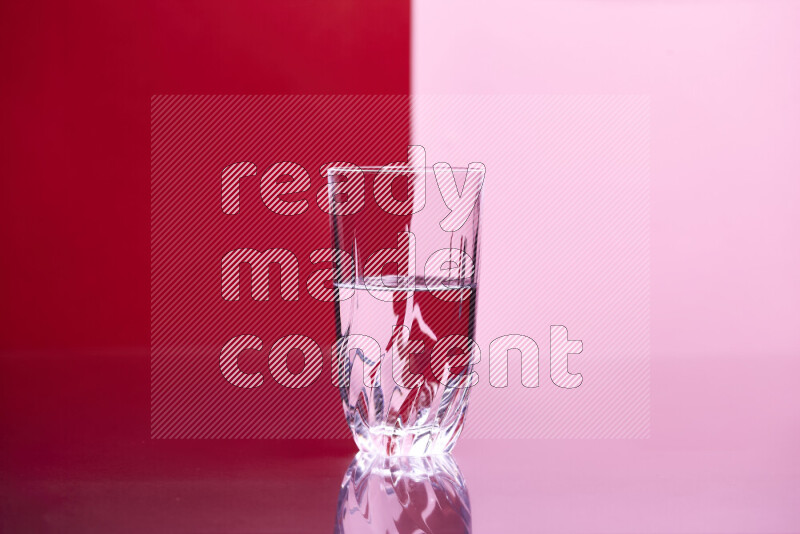 The image features a clear glassware filled with water, set against red and rose background