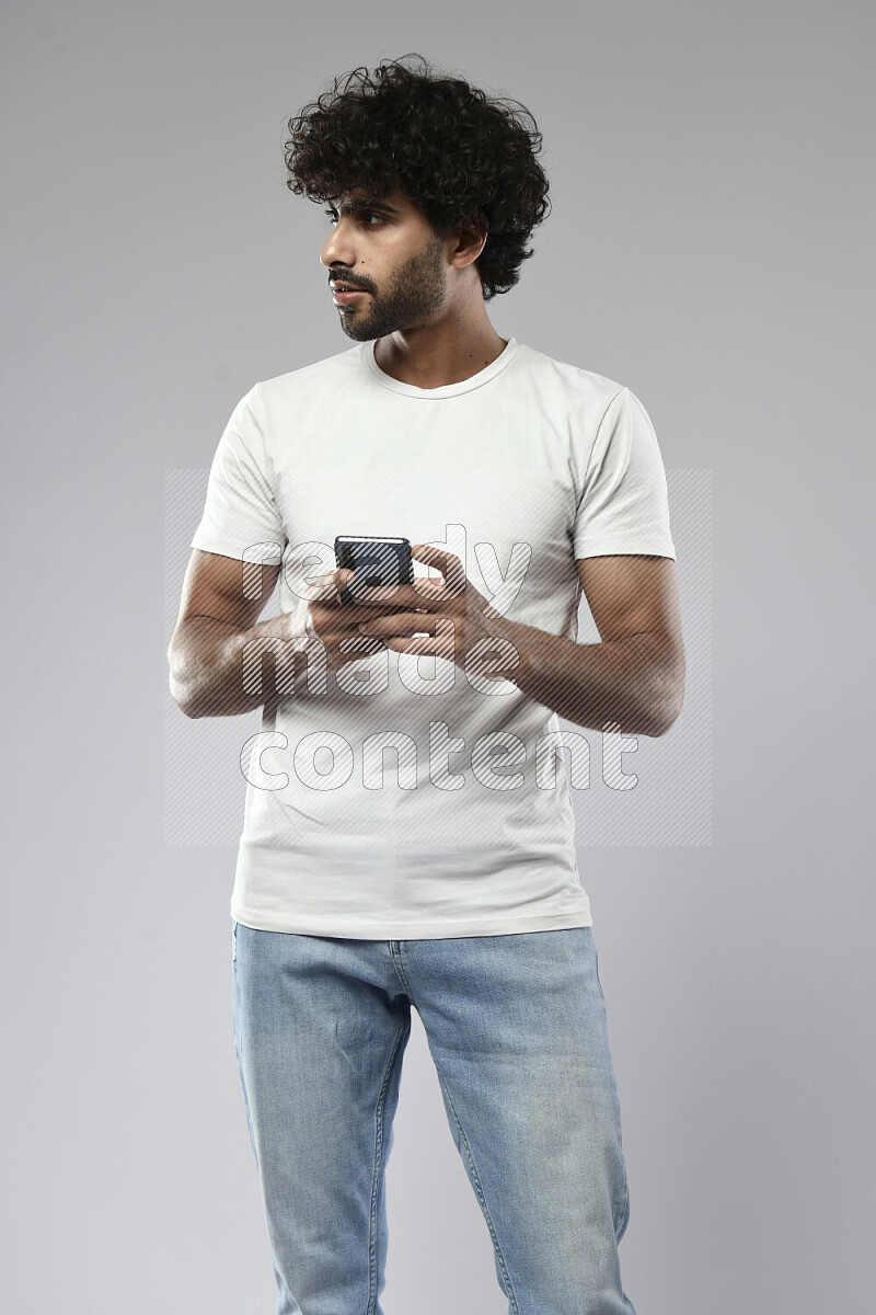 A man wearing casual standing and texting on the phone on white background