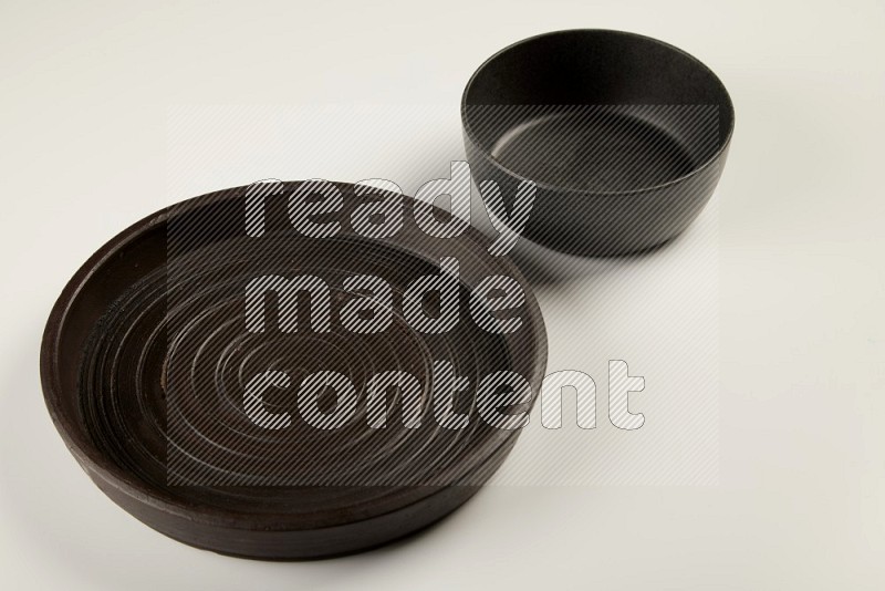 black pottery plate and black bowls on white background