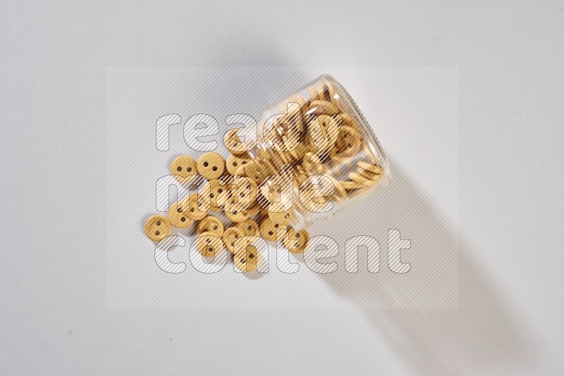 أزرار ملونة في وعاء زجاجي على خلفية رمادية