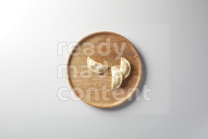 Three Sambosas on a wooden round plate on a white background