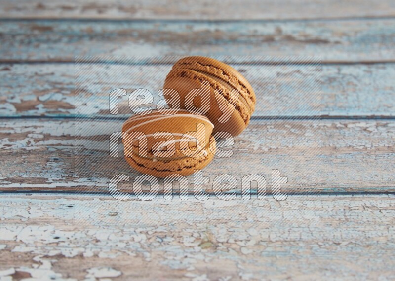 45º Shot of of two assorted Brown Irish Cream, and Brown Maple Taffy macarons  on light blue background