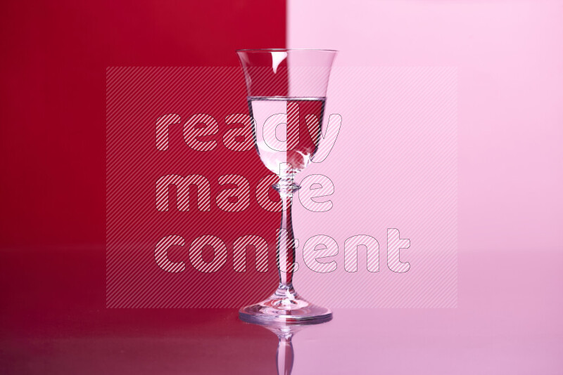 The image features a clear glassware filled with water, set against red and rose background