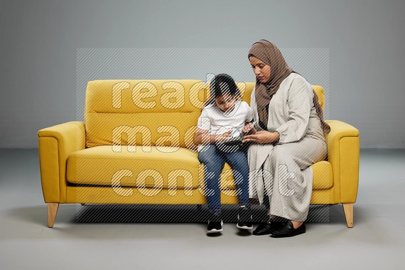 Mom and daughter sitting reading a book on gray background