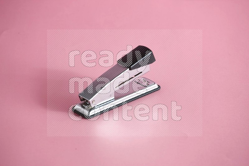 A metal stapler for paper on rose background