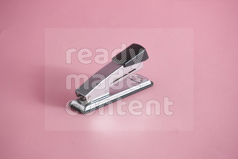 A metal stapler for paper on rose background