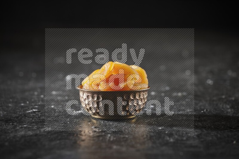 Dried fruits in a metal bowl in a dark setup