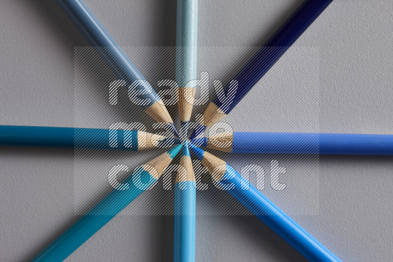 An arrangement of colored pencils in shades of blue on grey background