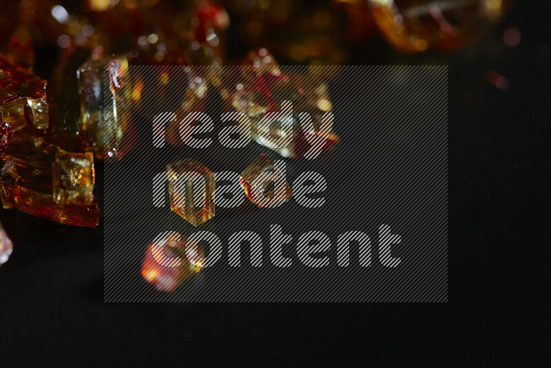 Transparent orange fragments of glass scattered on a black background