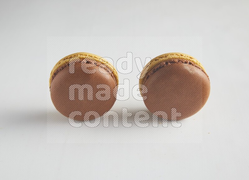 45º Shot of two Yellow and Brown Chai Latte macarons on white background