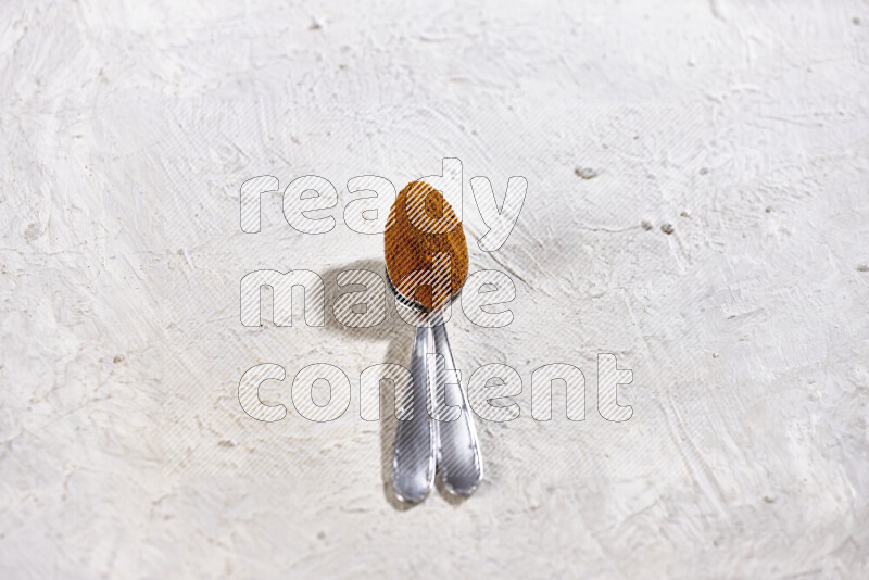 Two metal spoons full of ground paprika powder on white background