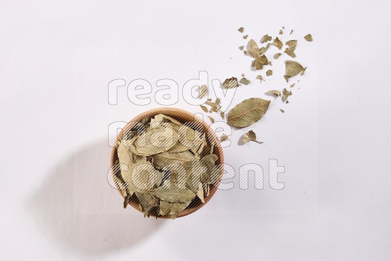 A wooden bowl filled with dried bay leaves on white flooring in different angles