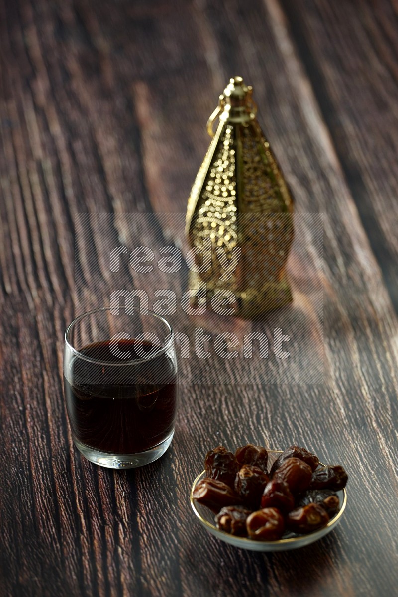 A golden lantern with different drinks, dates, nuts, prayer beads and quran on brown wooden background