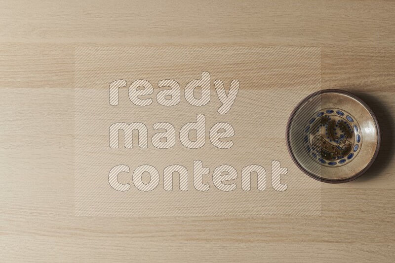 صحن فخاري مزخرف على خلفية خشبية فاتحة