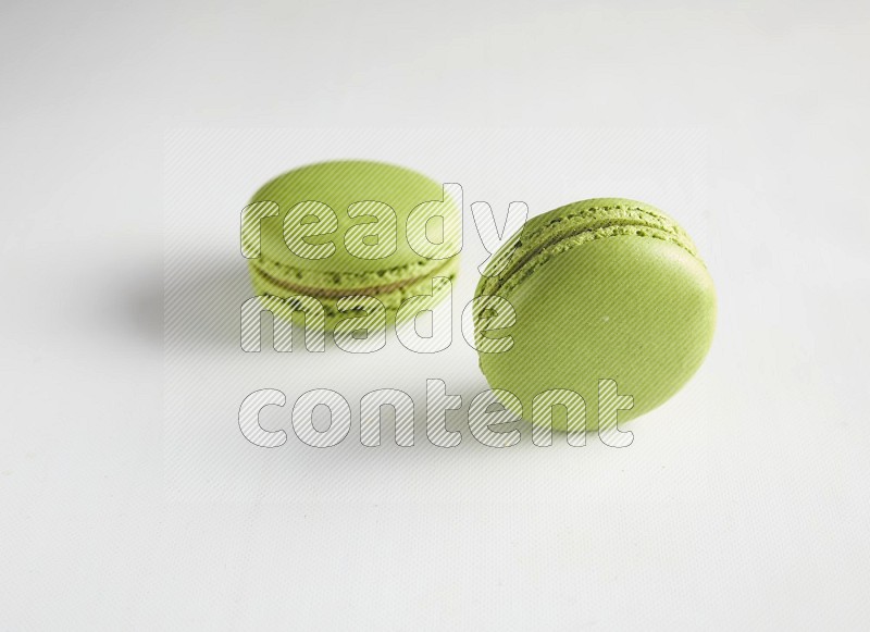 45º Shot of two Green Pistachio macarons on white background