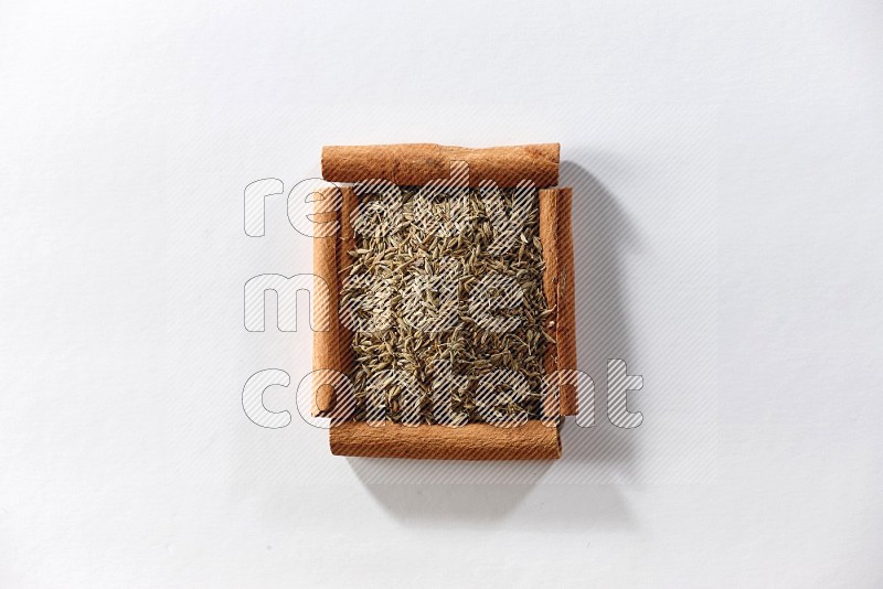 A single square of cinnamon sticks full of cumin on white flooring