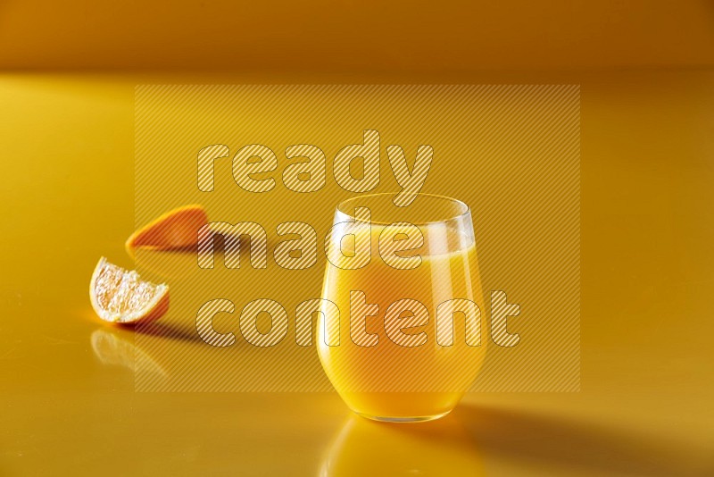 glass of orange juice on yellow background