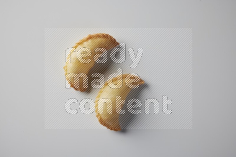 Two fried sambosa from a top angle on a white background