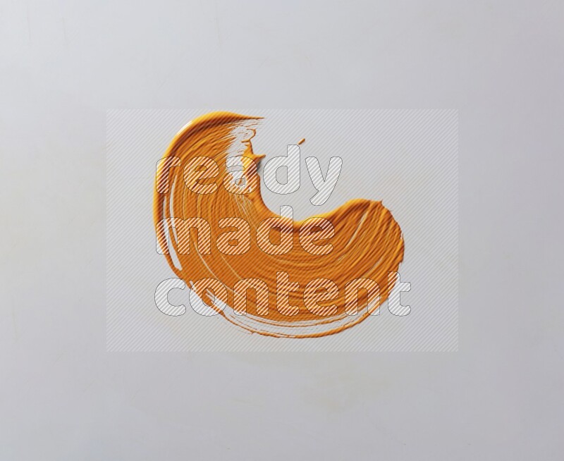 An orange curved painting brush stroke on a white background
