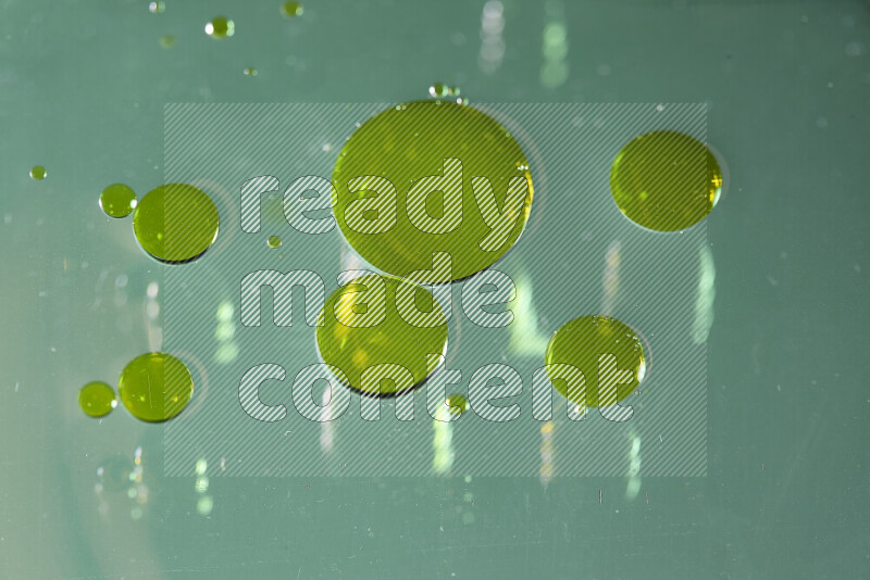 لقطات مقربة لقطرات ألوان مائية صفراء على سطح الزيت على خلفية خضراء