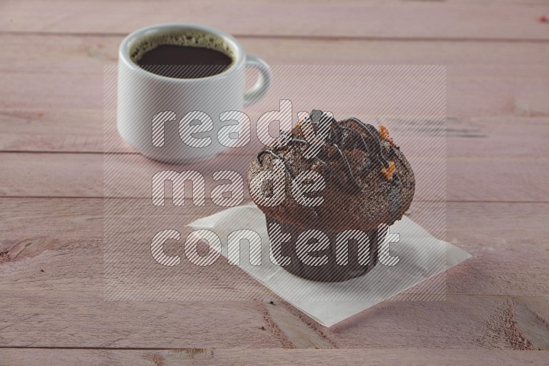 Chocolate cupcake topped with chocolate chips on a wooden pink background