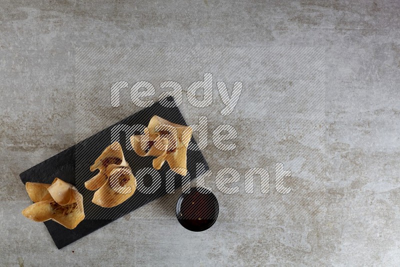 wonton cups with soy sauce ramkin on rectangle slate on grey textured counter top