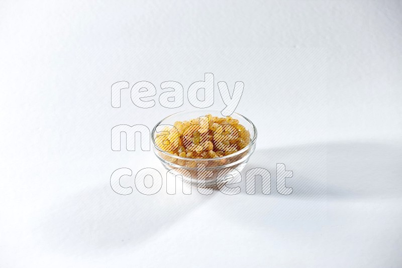 A glass bowl full of raisins on a white background in different angles