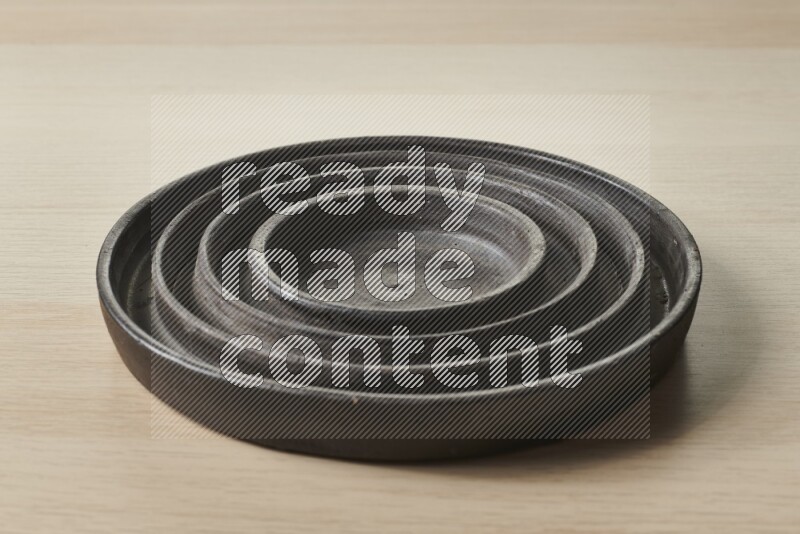 A pottery black ripple plate on light wooden background