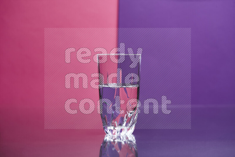 The image features a clear glassware filled with water set against pink and purple background