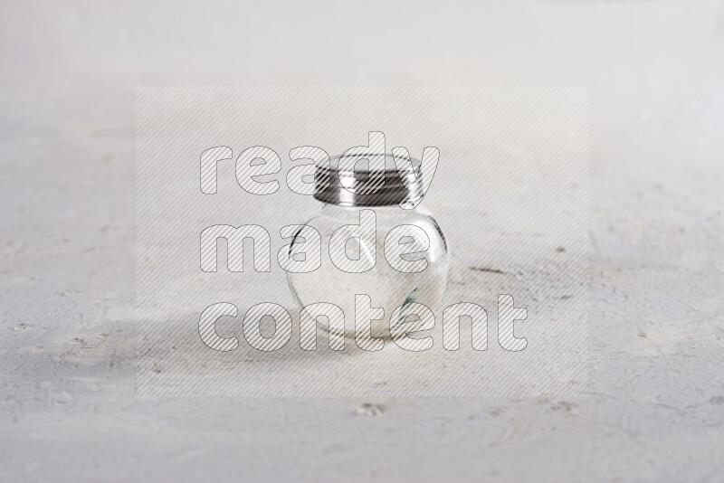 A glass jar full of coarse sea salt crystals on white background