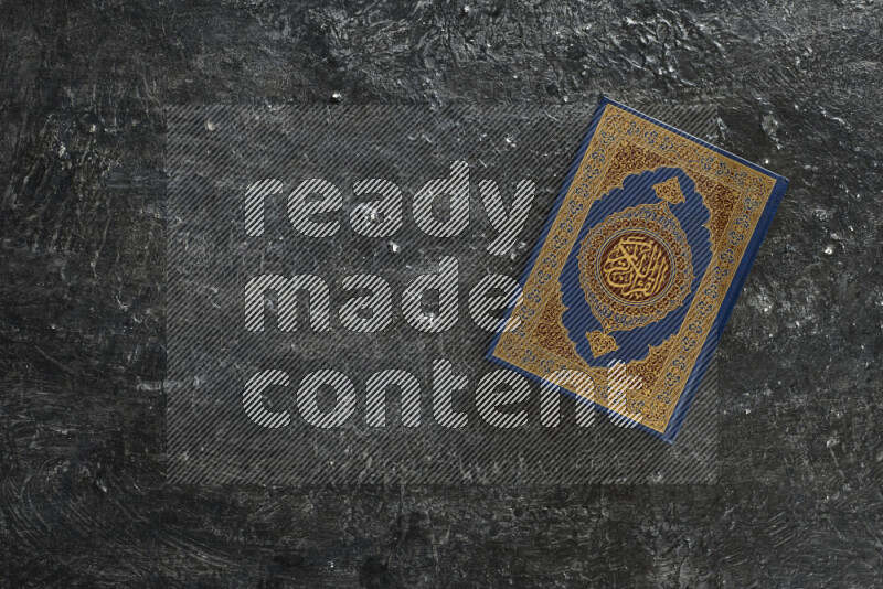 Quran with a prayer beads on textured black background