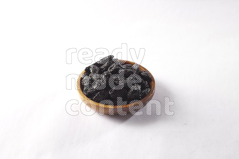 Dried plums in a wooden bowl on white background