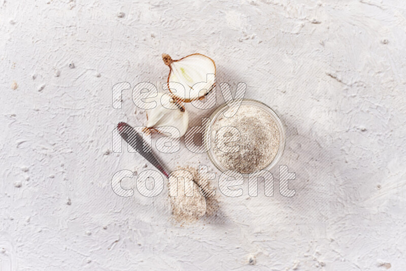 A glass jar full of onion powder on white background