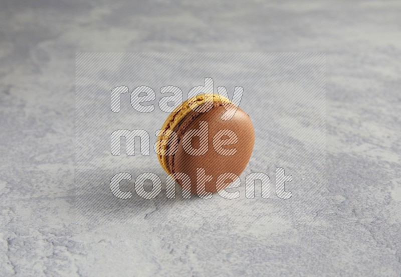 45º Shot of Yellow and Brown Chai Latte macaron on white  marble background