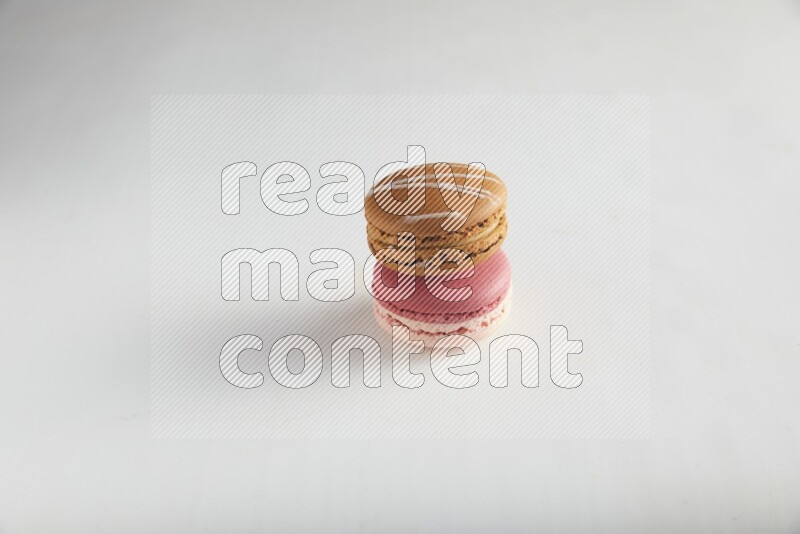 45º Shot of of two assorted Brown Irish Cream, and Pink Litchi Raspberry macarons on white background