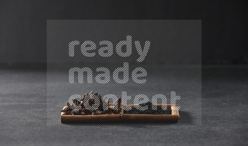 2 squares of cinnamon sticks full of black seeds and star anise on black flooring