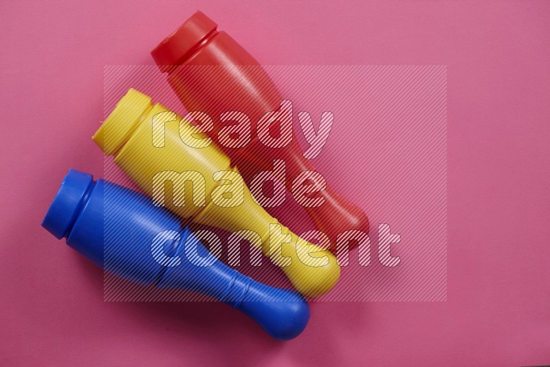 Multicolored plastic bowling pins on yellow, blue, green, orange and pink background in top view (kids toys)