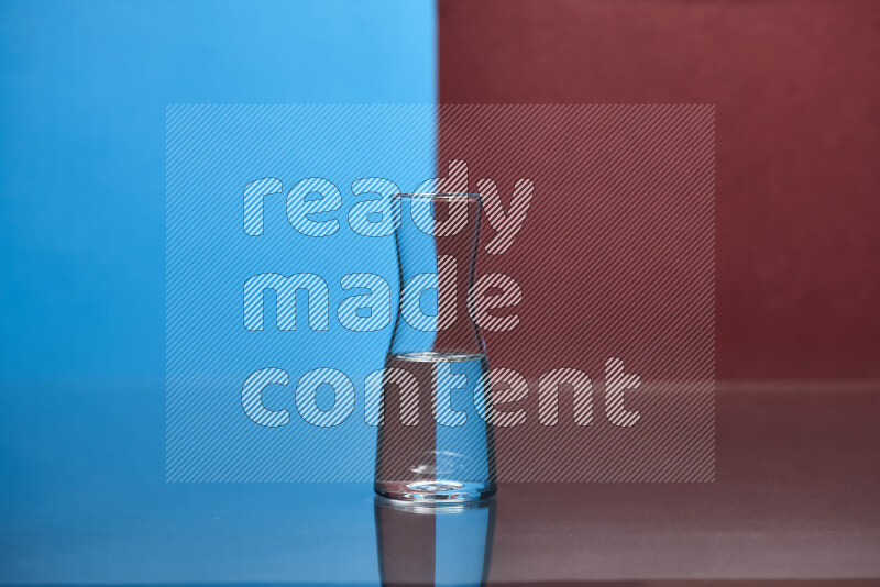 The image features a clear glassware filled with water, set against blue and dark red background