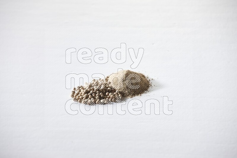 White pepper powder and pepper beads on white flooring